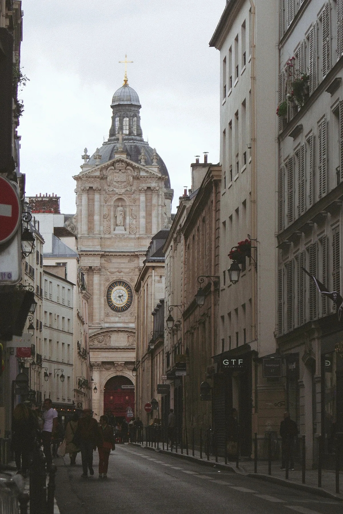 A narrow Paris street opening onto a historic domed church