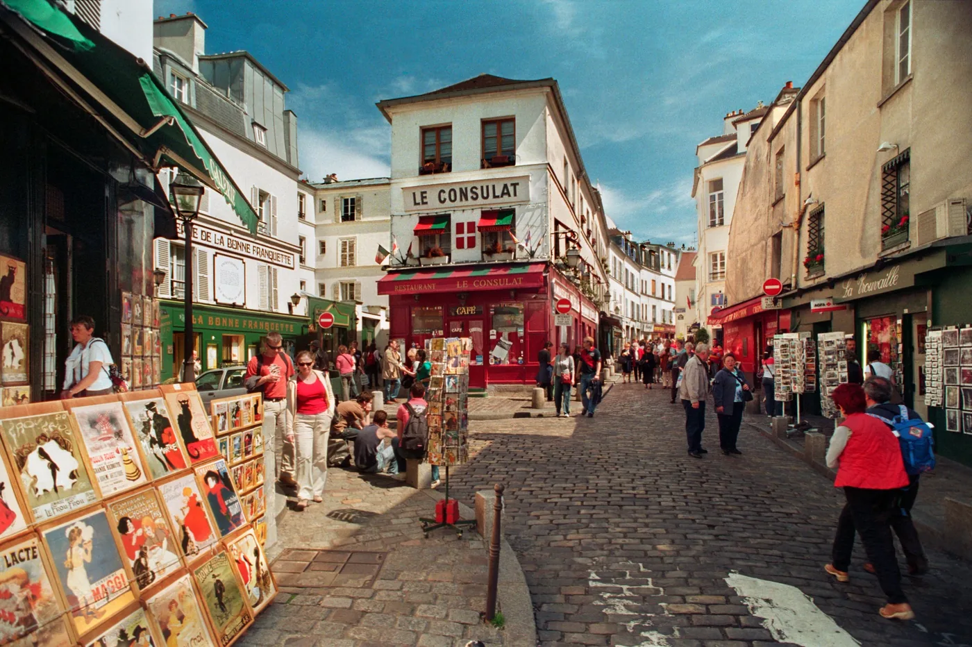 A lively Montmartre street with Le Consulat café and postcard stalls